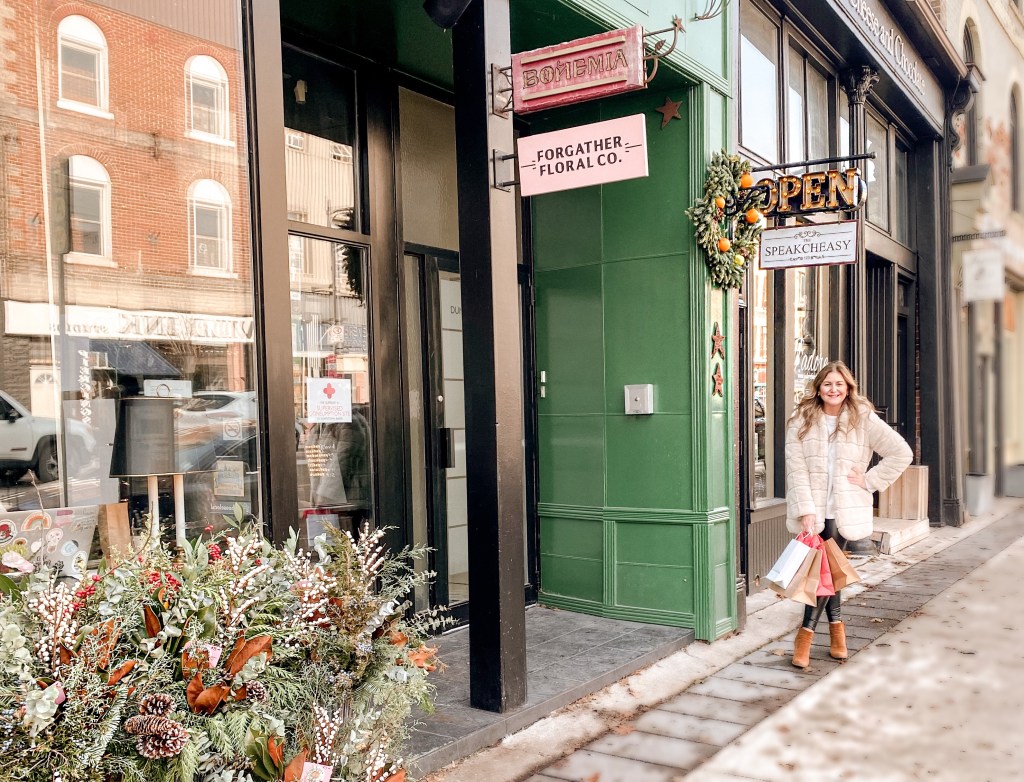 girl standing in front of a downtown building, with Christmas shopping bags